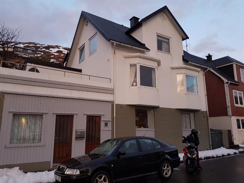 Budget Guesthouse Borgustova في Vestmanna: سيارة سوداء متوقفة أمام منزل