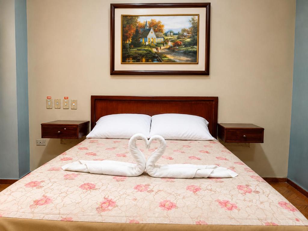 a bed with two towels in the shape of hearts at Hotel Milenio in Guayaquil