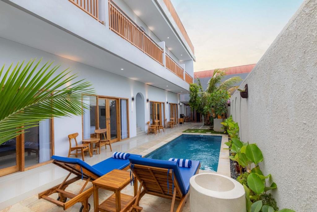 an outdoor patio with chairs and a swimming pool at Kubu YN Bali in Jimbaran
