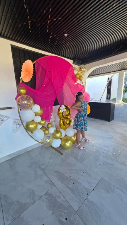 a young child standing next to a chair filled with balloons at Entre Mer et Volcan ,piscine chauffée au tampon in Bel Air