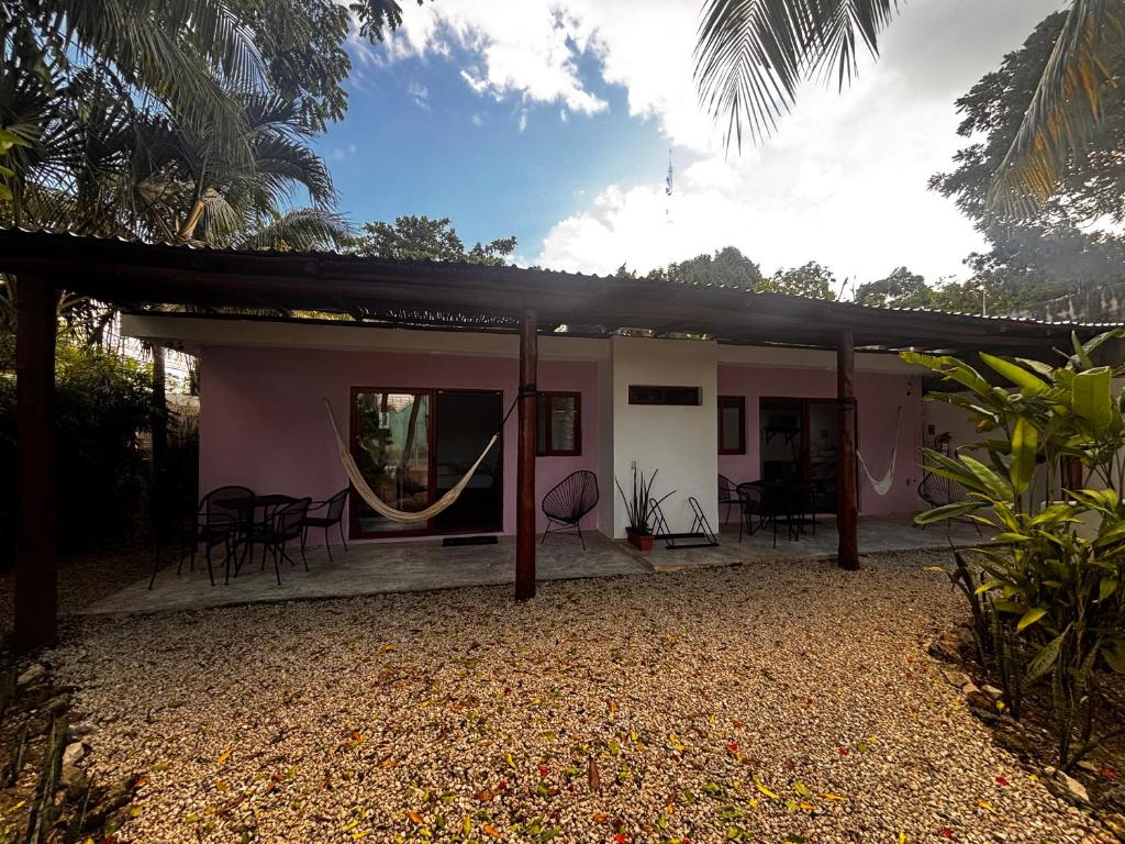 a pink house with chairs and tables in front of it at Tropical Garden Suites steps from the Lagoon in Bacalar