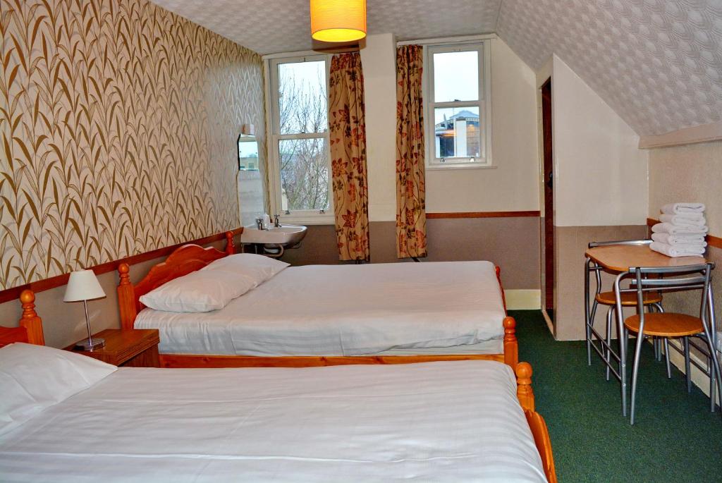 a hotel room with two beds and a table at London Visitors Hotel in London