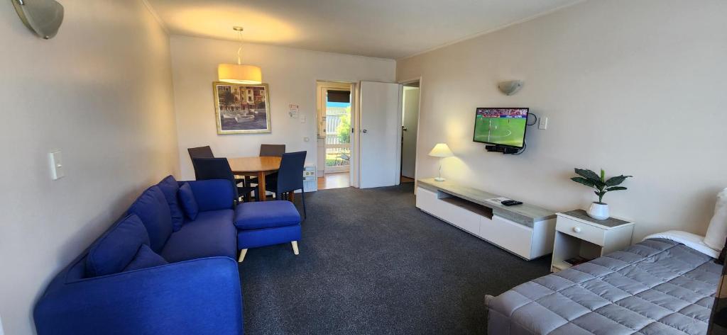 a living room with a blue couch and a tv at Aalton Motel in Christchurch