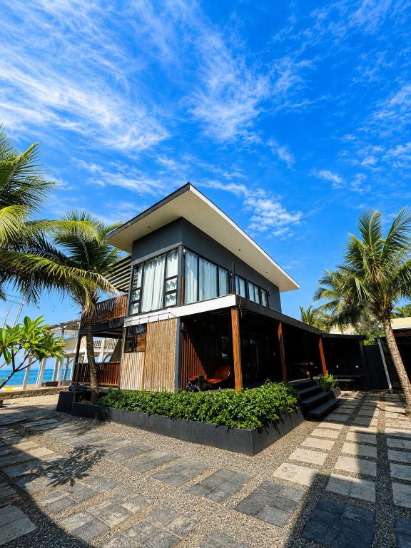 a house with palm trees in front of it at Upgrade Beach Resort Infanta Quezon in Infanta