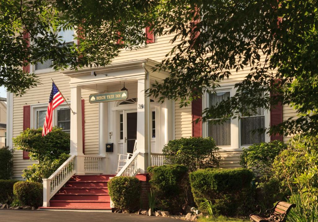 Uma casa branca com uma bandeira americana à frente. em Beech Tree Inn and Cottage em Newport