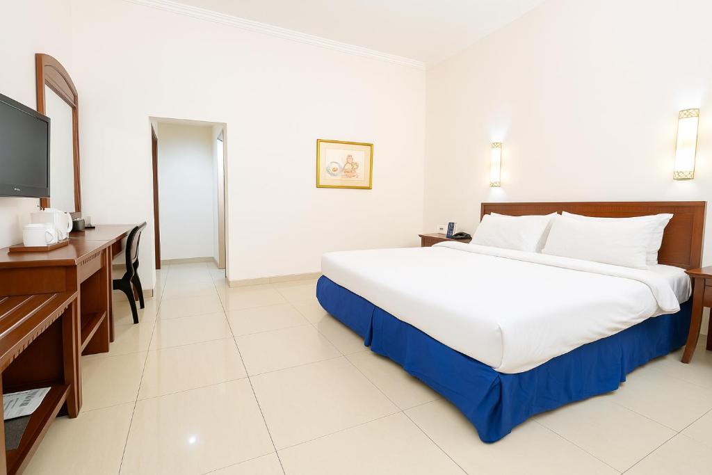 a bedroom with a large bed and a flat screen tv at Grand Orchid Hotel Solo in Solo