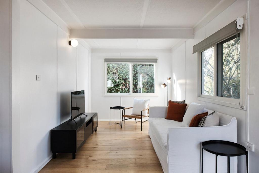 a white living room with a white couch and a table at Cedar Lodge in Braidwood