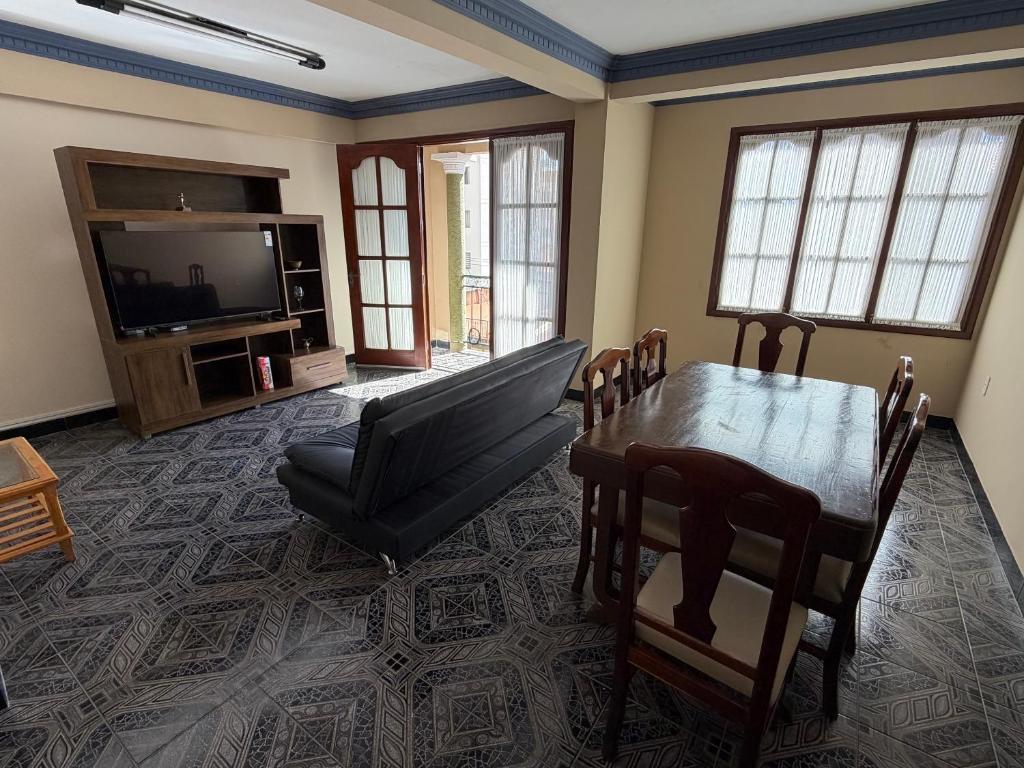 a living room with a table and a couch and a television at Altos de Belgrano Suites in Tarija
