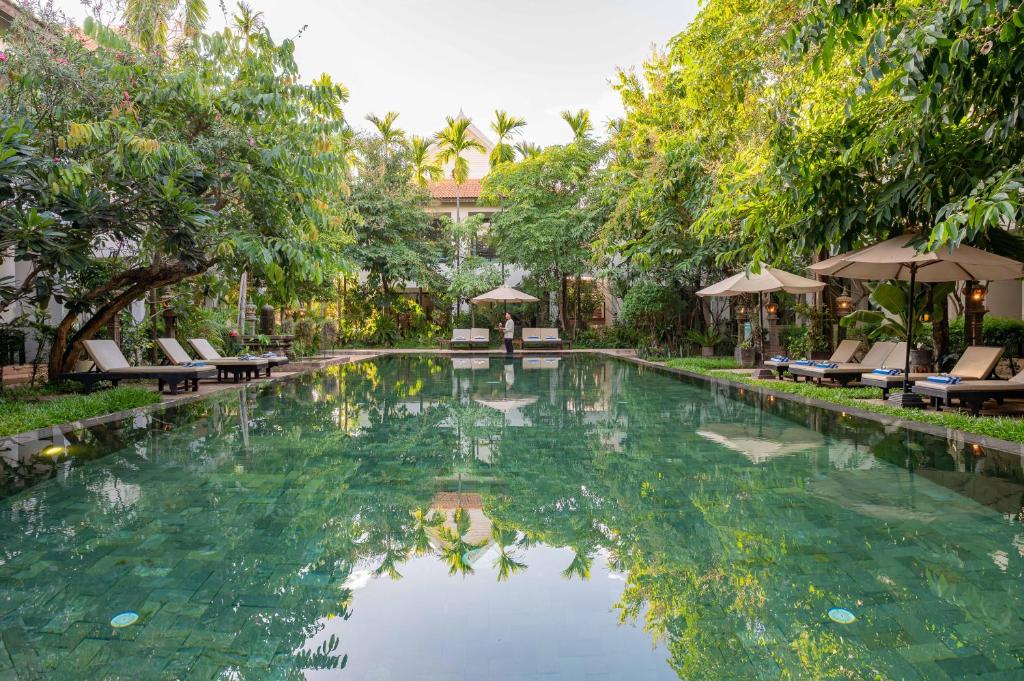 a swimming pool in a resort with chairs and trees at Tanei Angkor Resort and Spa in Siem Reap