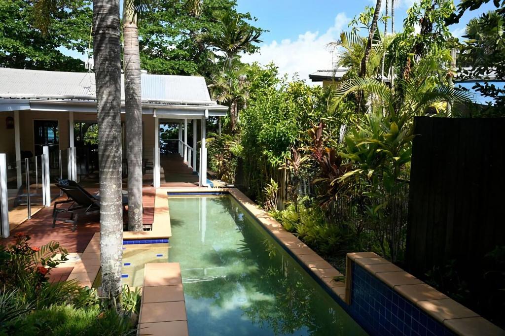 a swimming pool in front of a house with palm trees at Seasons at South Mission Beach in South Mission Beach