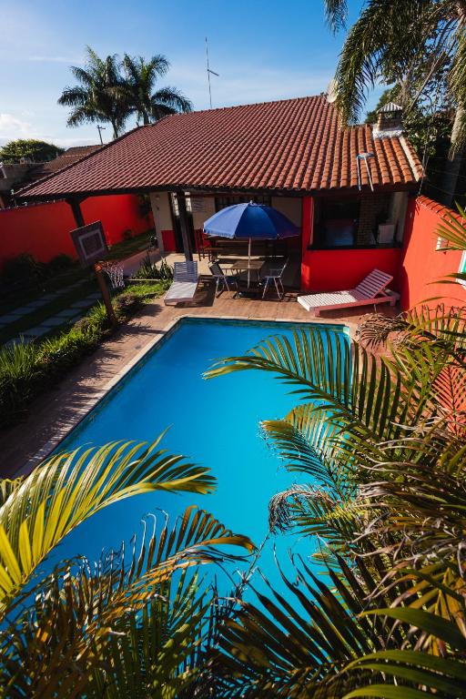 a blue swimming pool in front of a house at Sinuca, churrasqueira e fogueira a 300 metros do mar in Itanhaém