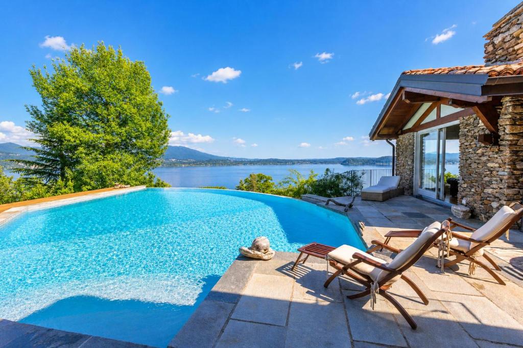a swimming pool with chairs and a house at Paradis Relais Infinity Pool Lake View in Belgirate