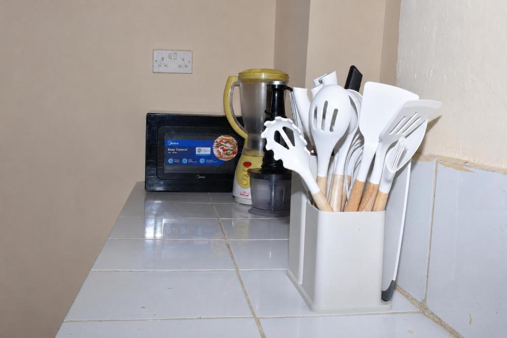 a kitchen counter with a container of utensils at Maya Homestay in Ukunda