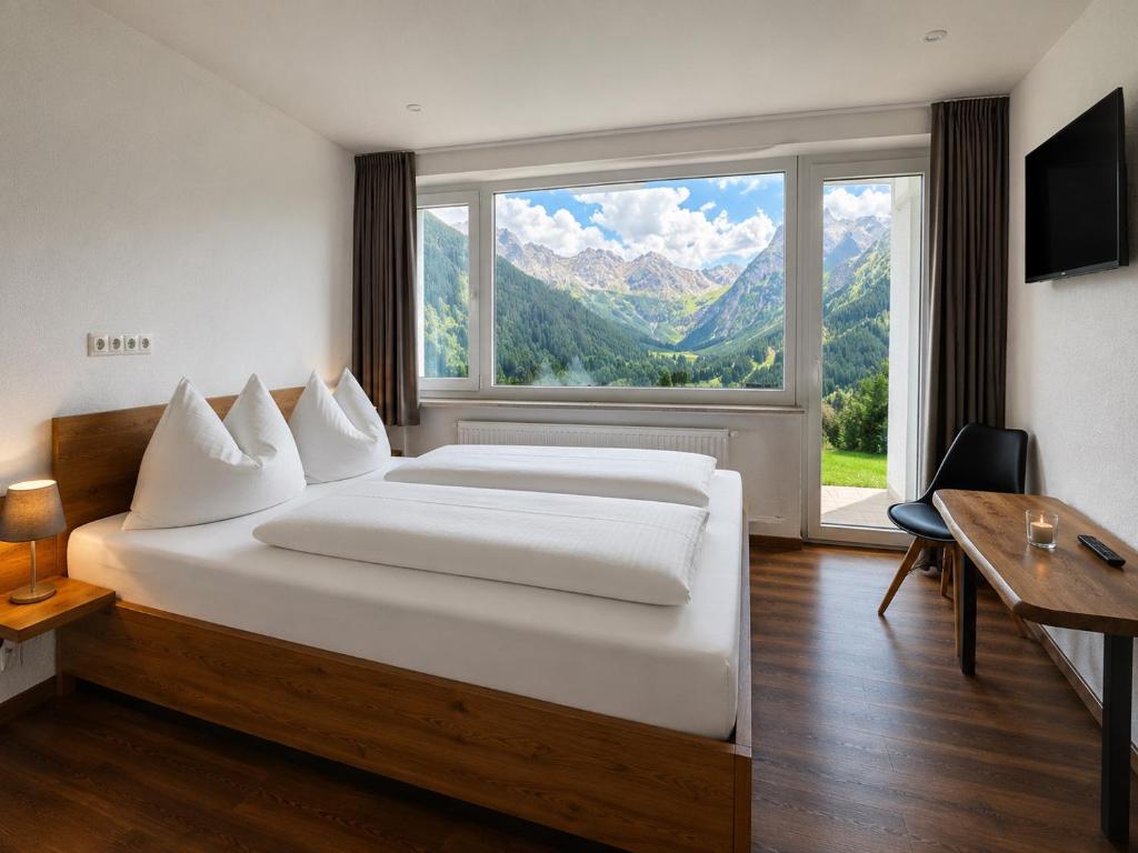 a bedroom with a large bed and a large window at Apartmenthaus Ahorn in Mittelberg