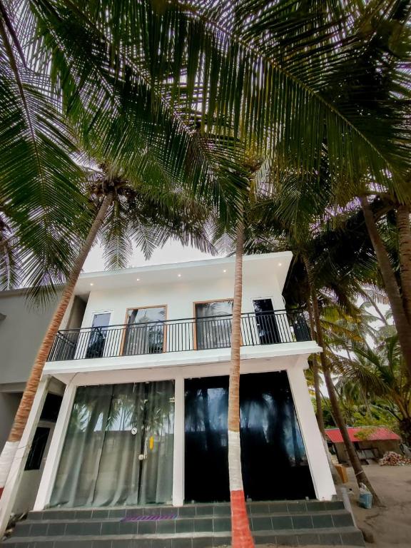 a white house with palm trees in front of it at La Paraso Agatti in Agatti