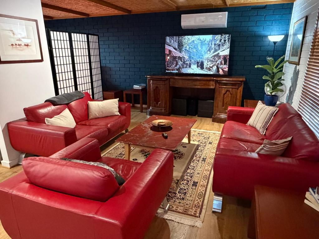 a living room with red leather furniture and a tv at Oasis at Aldinga Beach in Aldinga Beach