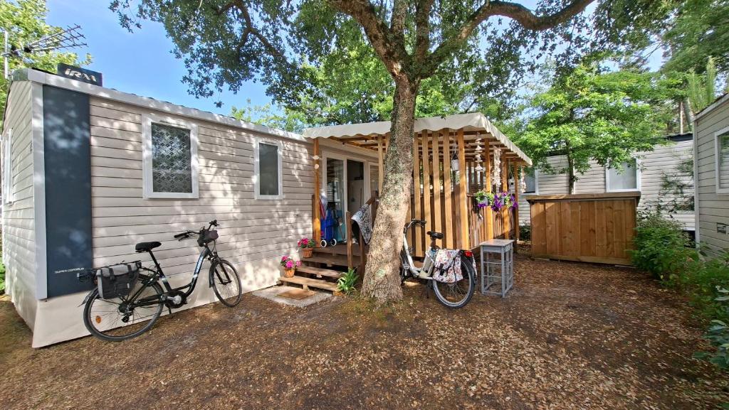 a tiny house with two bikes parked next to a tree at Mobil home 3ch, clim, bord de mer in Seignosse