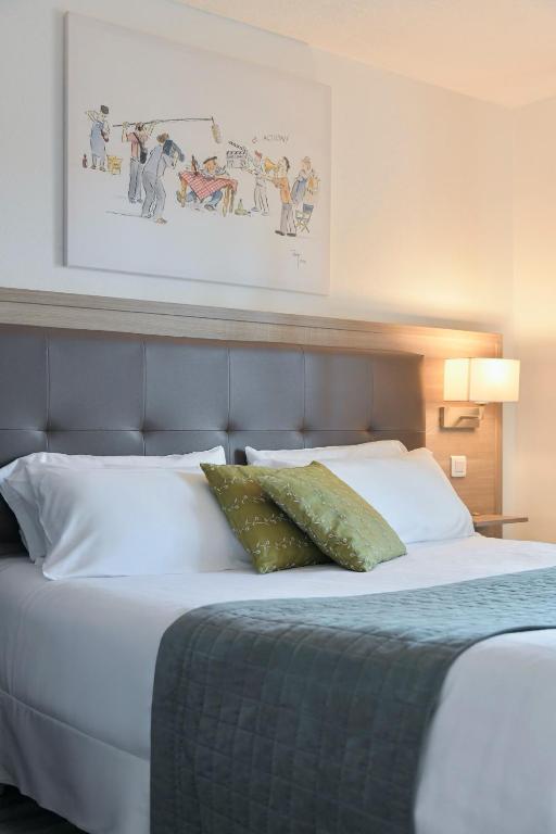 a bed with white sheets and pillows in a room at Hôtel Les Comtes de Pardiac in Marciac