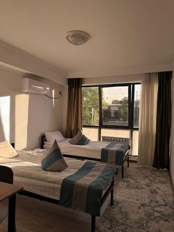 a hotel room with three beds and a window at River guest house in Osh