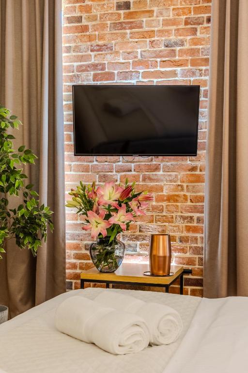 a tv hanging on a brick wall with a bed at Hotel Jazz Market Square Wroclaw in Wrocław