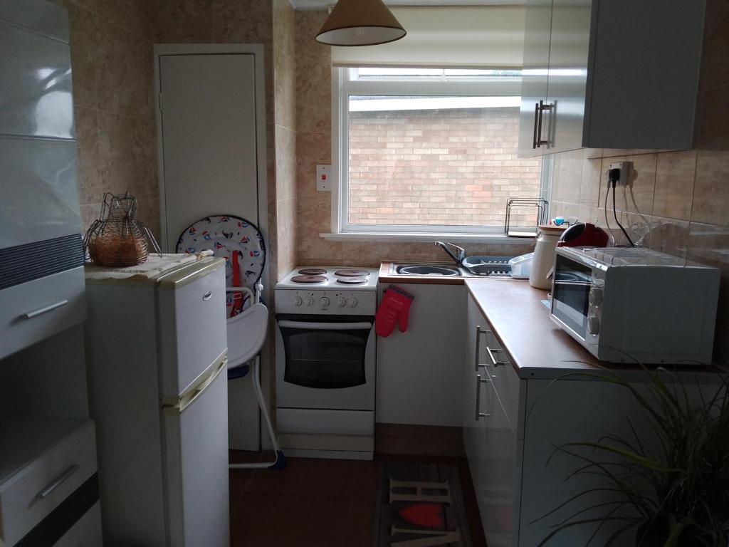 a small kitchen with a stove and a microwave at SHORTIEs STAYS in Hemsby