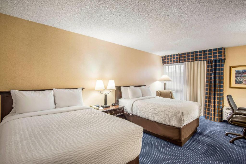 a hotel room with two beds and a chair at Clarion Inn Grand Junction Airport in Grand Junction