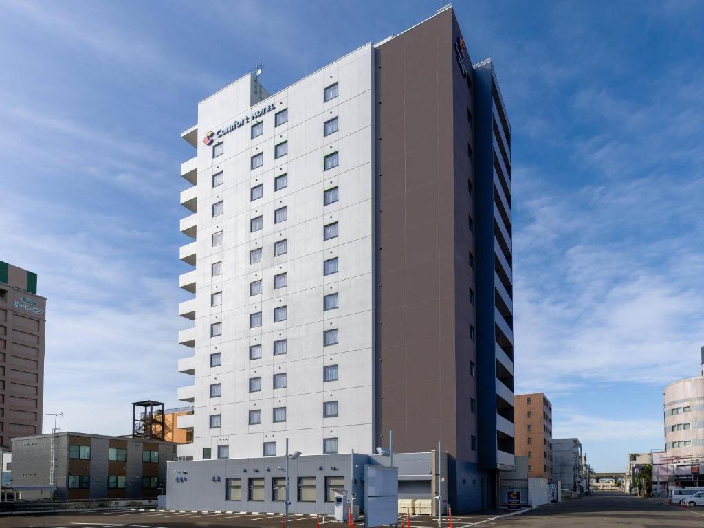 a tall white hotel building in a city at Comfort Hotel Chitose in Chitose
