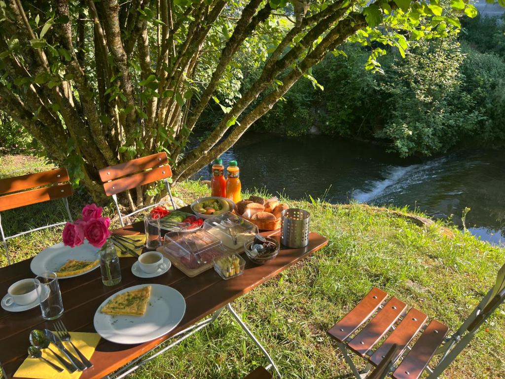 a picnic table with food on it next to a river at Hotel Hirsch Fluorn Schwarzwald in Fluorn