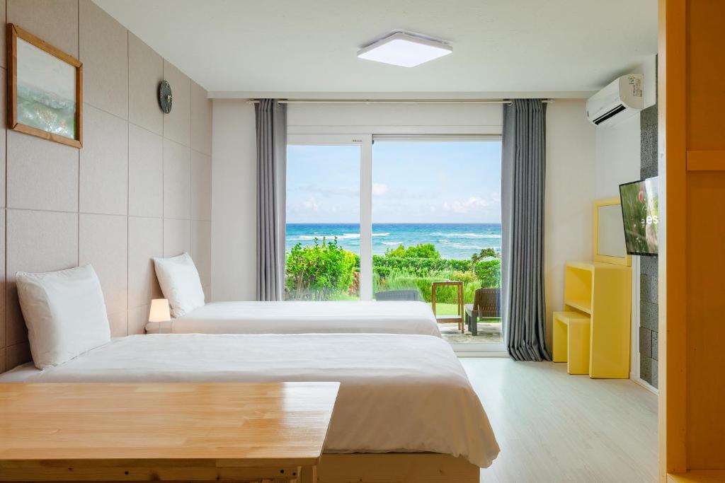 two beds in a room with a view of the ocean at Jeju Turning point Pension in Seogwipo
