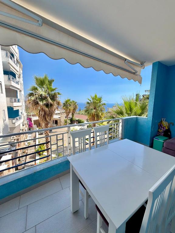 a white table and chairs on a balcony with palm trees at Seaview Apartment in Dhërmi