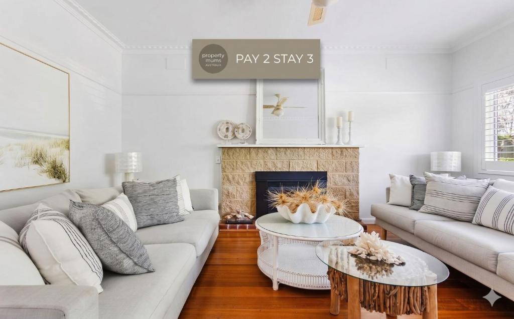 a living room with white furniture and a fireplace at Waves on Rye in Rye