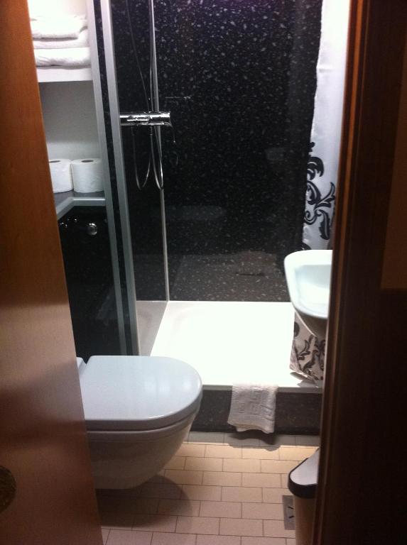 a bathroom with a shower with a toilet and a sink at London Visitors Hotel in London