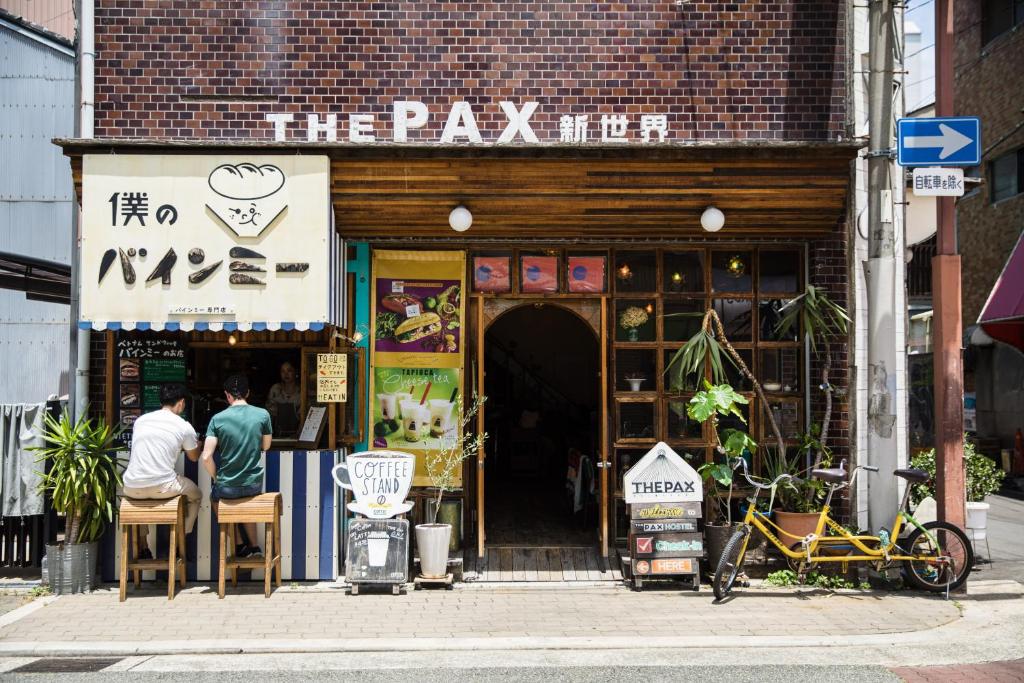 two men sitting in front of a shop on the street at The Pax Hostel in Osaka