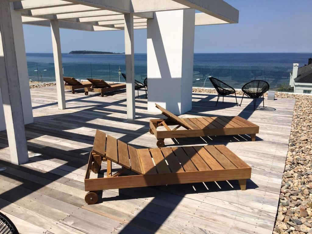 una fila de bancos de madera sentados en una terraza con vistas al océano en Apartamento Rambla 24, en Punta del Este