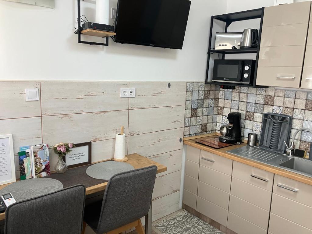 a kitchen with a table with chairs and a microwave at Móra apartman 3. in Kiskunfélegyháza