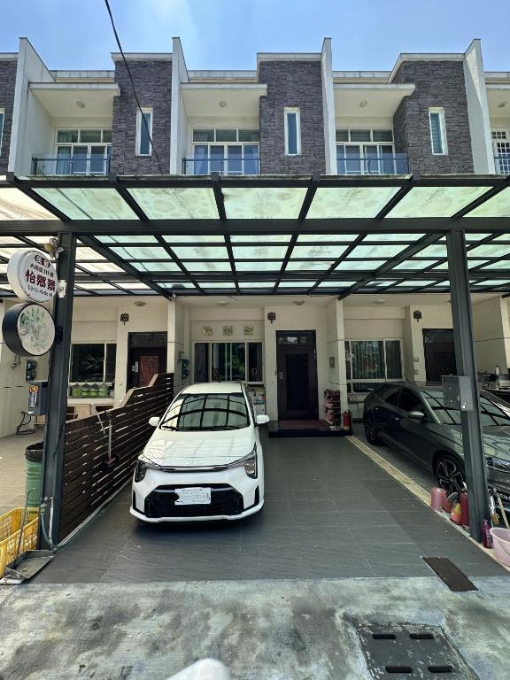 a white car parked in a parking lot in front of a house at Yixiangjing Guesthouse in Zhushan