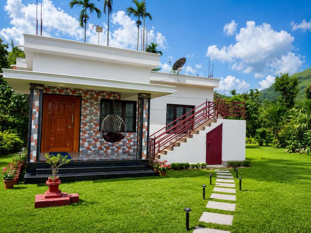 a small white house with a grass yard at Ragikana homestsy in Kalasa