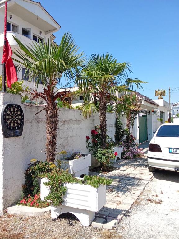 a house with palm trees and plants in front of it at Rooms New DiamonD in Durrës