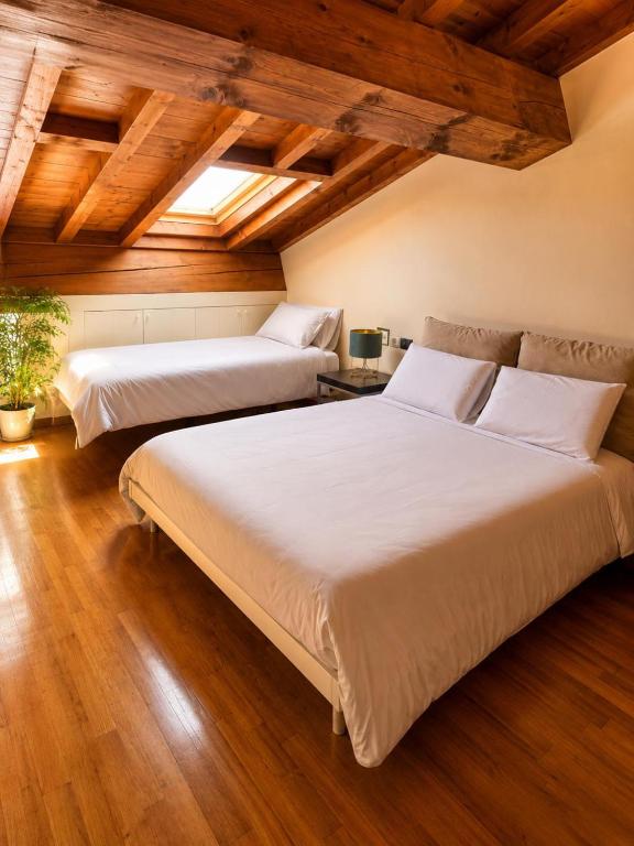 Zwei Betten in einem Zimmer mit Holzdecke und Holzboden in der Unterkunft Spazio 28 - free private parking in Mantua