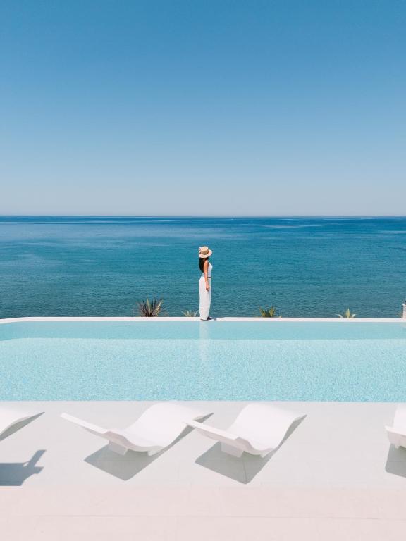 a woman in a hat standing next to a swimming pool at KAAB Boutique Hotel in Ulcinj