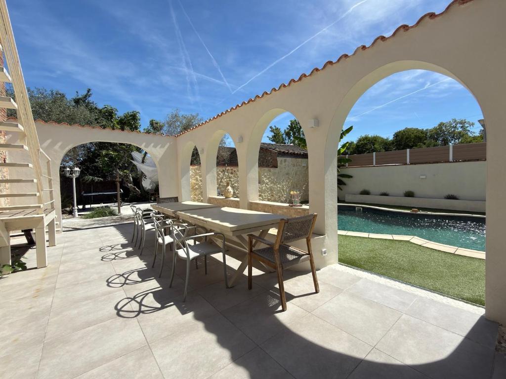 a patio with a table and chairs and a pool at L'Oliveraie d'Eurocentre - Piscine, Parking & Petit-Déjeuner in Castelnau-dʼEstrétefonds