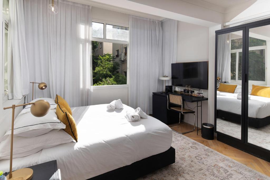 a bedroom with a large white bed and a desk at Theodor Rothschild Tel-Aviv in Tel Aviv