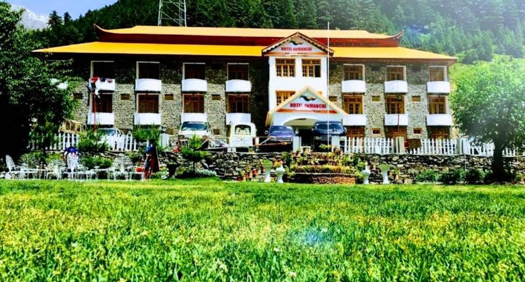 a large building with a garden in front of it at Hotel Demanchi Naran in Naran