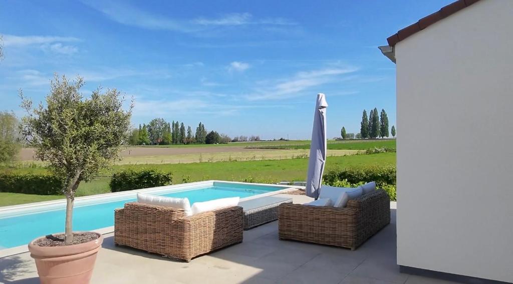 a swimming pool with an umbrella and wicker chairs next to a swimming pool at Tyne View Hideaway in Zonnebeke