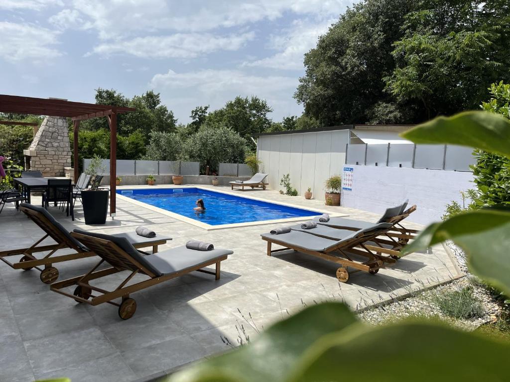 a swimming pool with two lounge chairs and a table at Holiday house Gabi Istria in Brtonigla