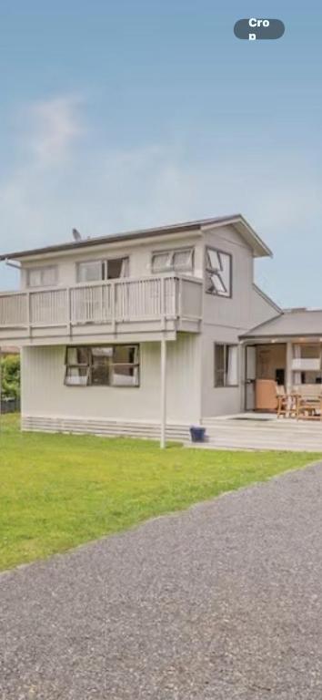a large white house with a balcony and grass at Beach Break Inn in Whitianga