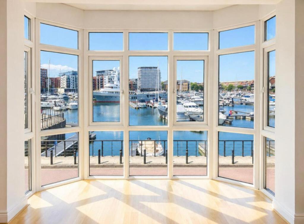 an empty room with large windows looking out at a harbor at Waterside House in Southampton