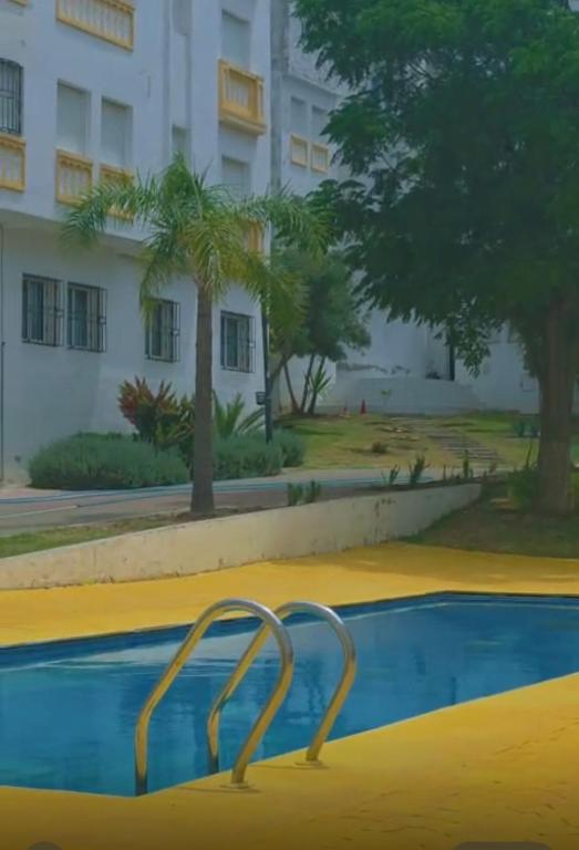 an empty swimming pool in front of a building at Appartement tangier airport in Hajreien