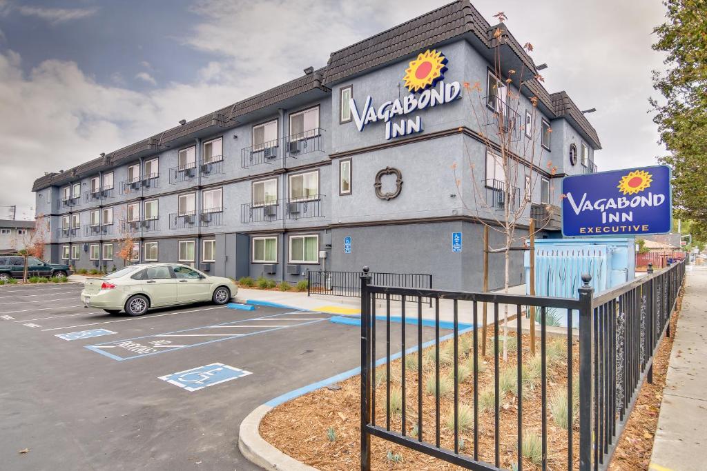 a building with a car parked in a parking lot at Vagabond Inn Executive Hayward in Hayward