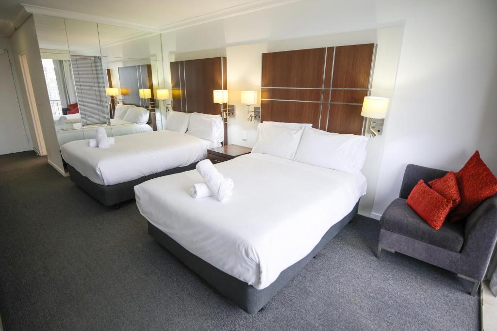 a hotel room with two beds and a chair at Beachside Studio with Stunning Ocean View in Gold Coast